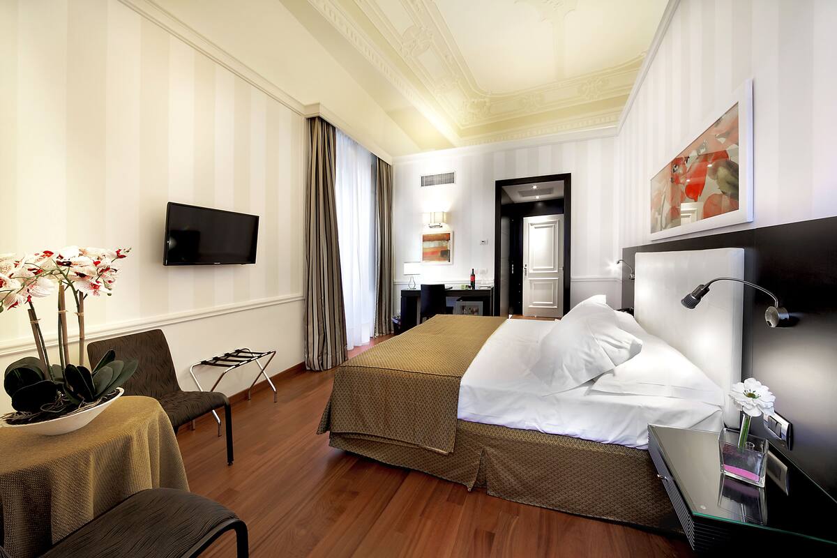 A hotel room with a bed, a TV, a desk, and a chair.