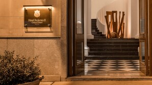 The entrance to Hotel Federico II, featuring a checkered floor, a staircase, and a modern light fixture above the entrance. - Central Palace Hotel Federico II (Palermo)