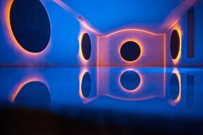 Una habitación con aberturas circulares en las paredes y un suelo reflectante.
