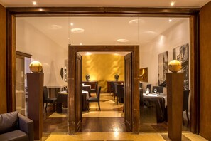 A hotel lobby with a wooden-framed entrance leading to a dining area with tables and chairs. - Central Palace Hotel Federico II (Palermo)