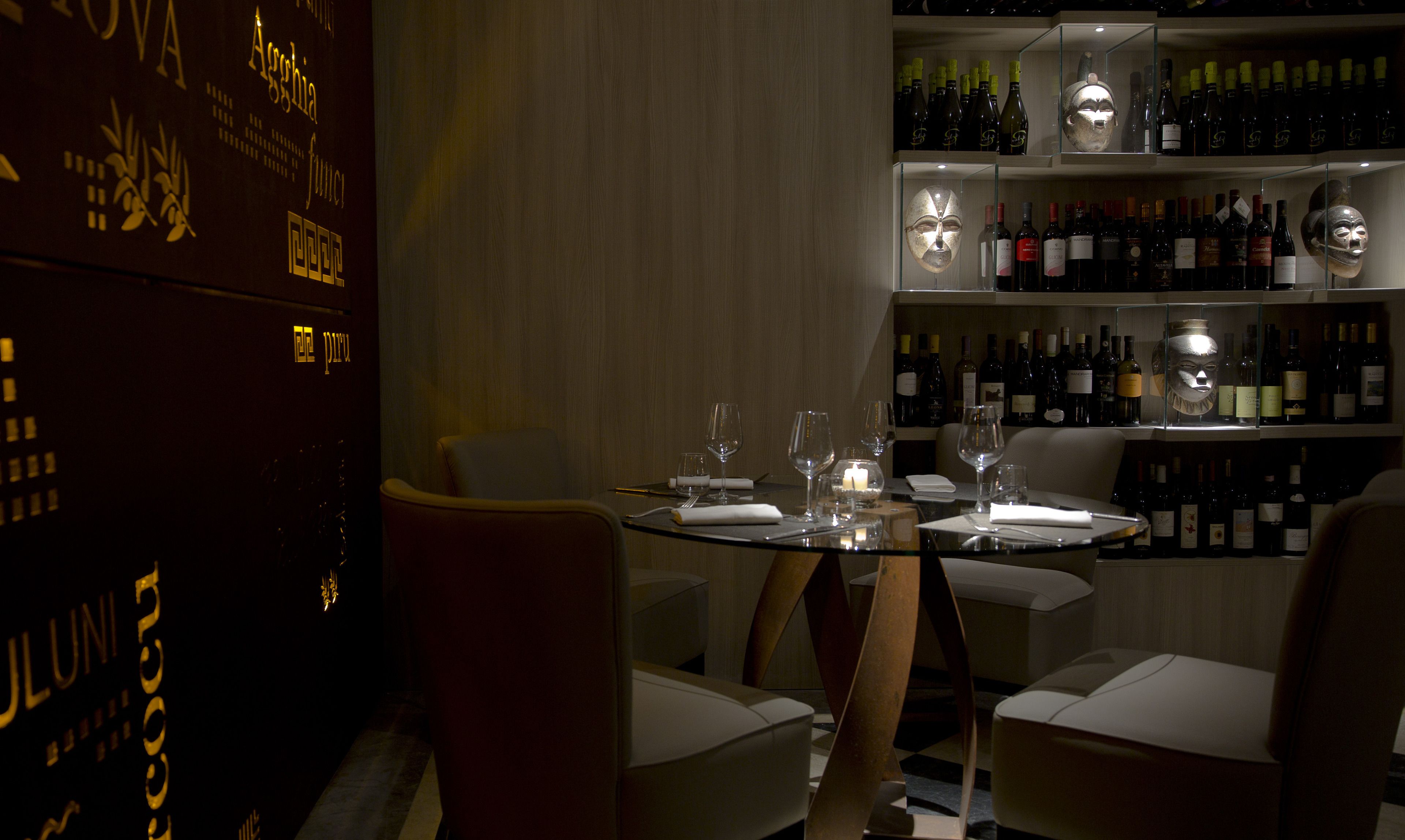 A dimly lit restaurant with a round table set for two, surrounded by chairs.