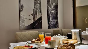 Un desayuno con croissants, una fuente de fruta y una taza de café sobre una mesa, con vistas a la ciudad al fondo.