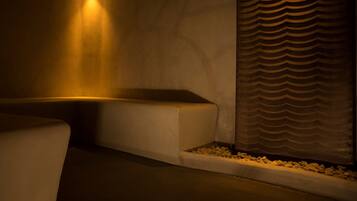 A dimly lit spa area with a curved bench and a textured wall.