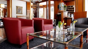 A hotel lobby with red sofas, a glass coffee table, and a fireplace. - Ambassador Parkhotel (Munich)