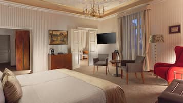 Una habitación de hotel con una cama grande, un escritorio, un televisor y un sillón rojo.