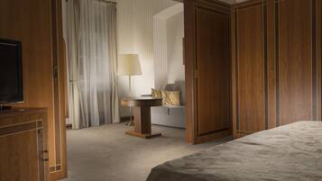 Quarto de hotel com cama, televisão, escrivaninha e sofá.