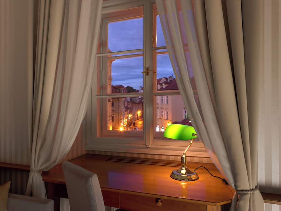 A room with a desk, a lamp, and a window with curtains.