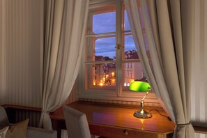 A room with a desk, a lamp, and a window with curtains.