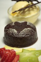 A dessert plate with a chocolate lava cake, a scoop of vanilla ice cream, and fresh fruit.