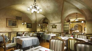 Un ristorante con diversi tavoli, sedie e un lampadario.