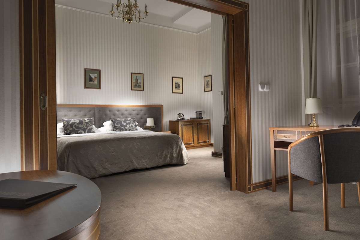 Quarto de hotel com cama, escrivaninha, cadeira e um pequeno armário.