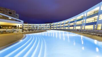 Ein modernes Hotel mit großem Innenpool, mehreren Etagen und einer gewölbten Glasfassade.