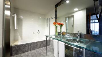 Une salle de bain moderne dotée d’une douche à parois de verre, d’un lavabo en verre et d’un grand miroir.