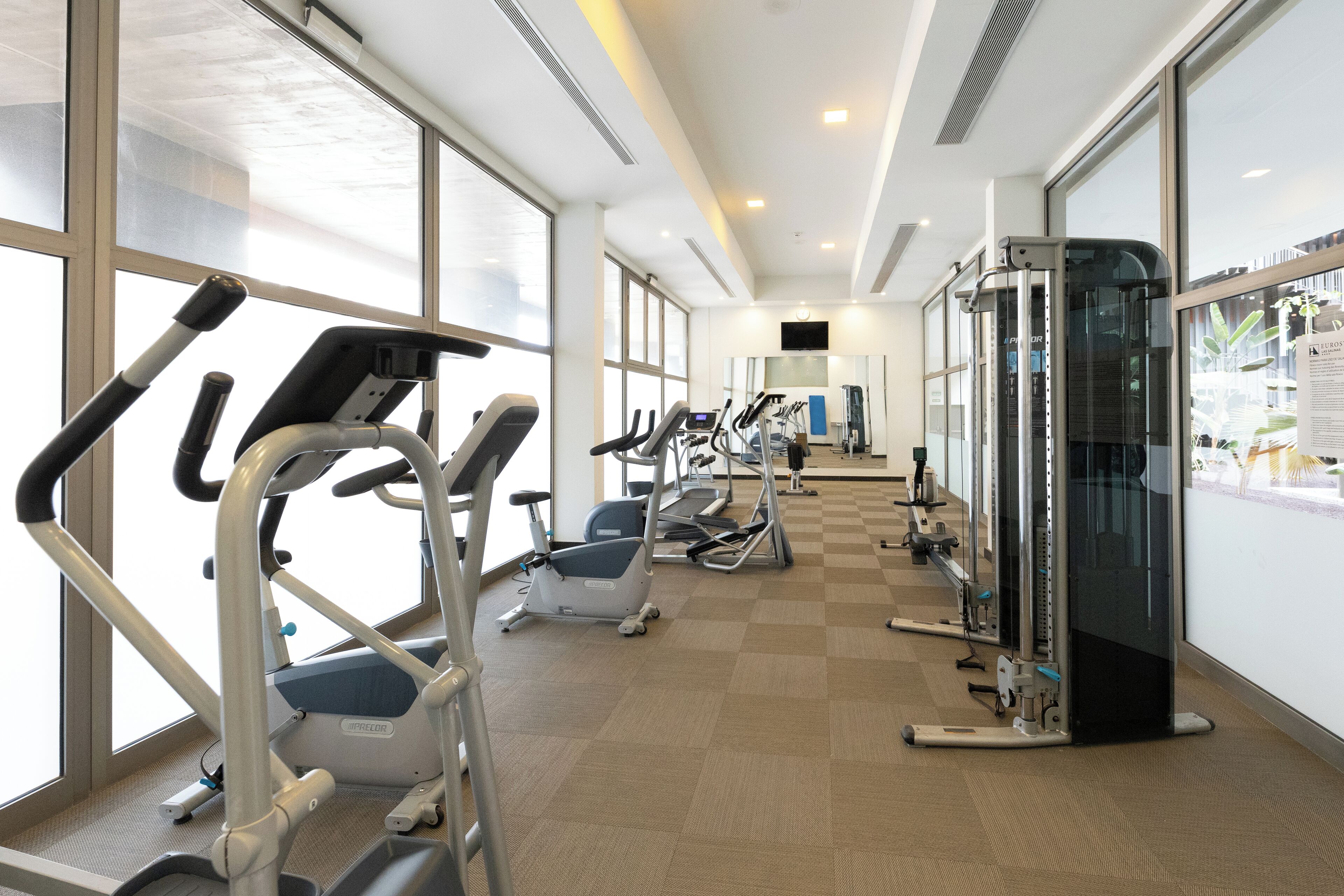 Une salle de sport équipée de tapis de course, de vélos elliptiques et de matériel de musculation.
