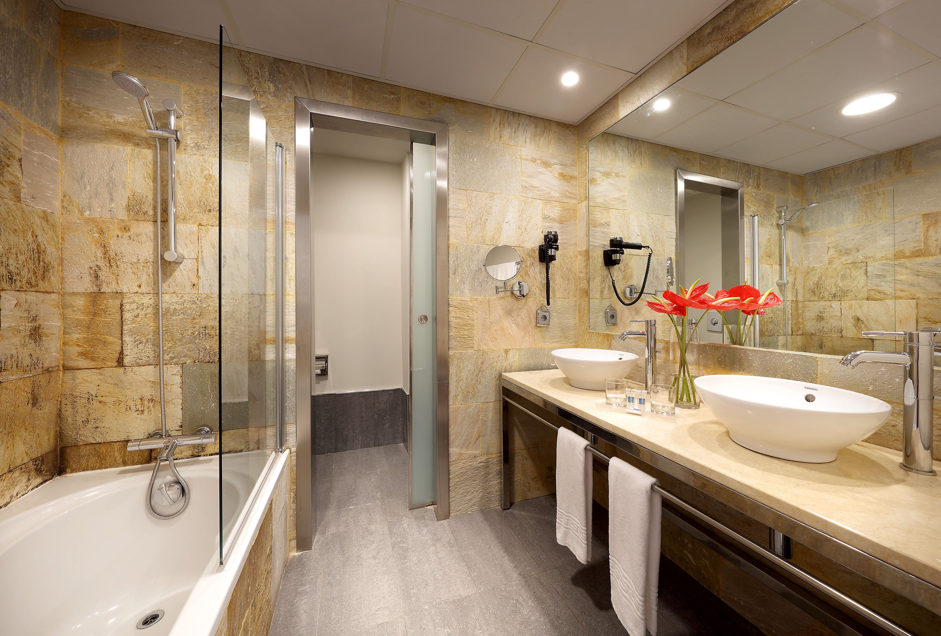 Un baño moderno con bañera, dos lavamanos, un espejo grande y cabina de ducha.