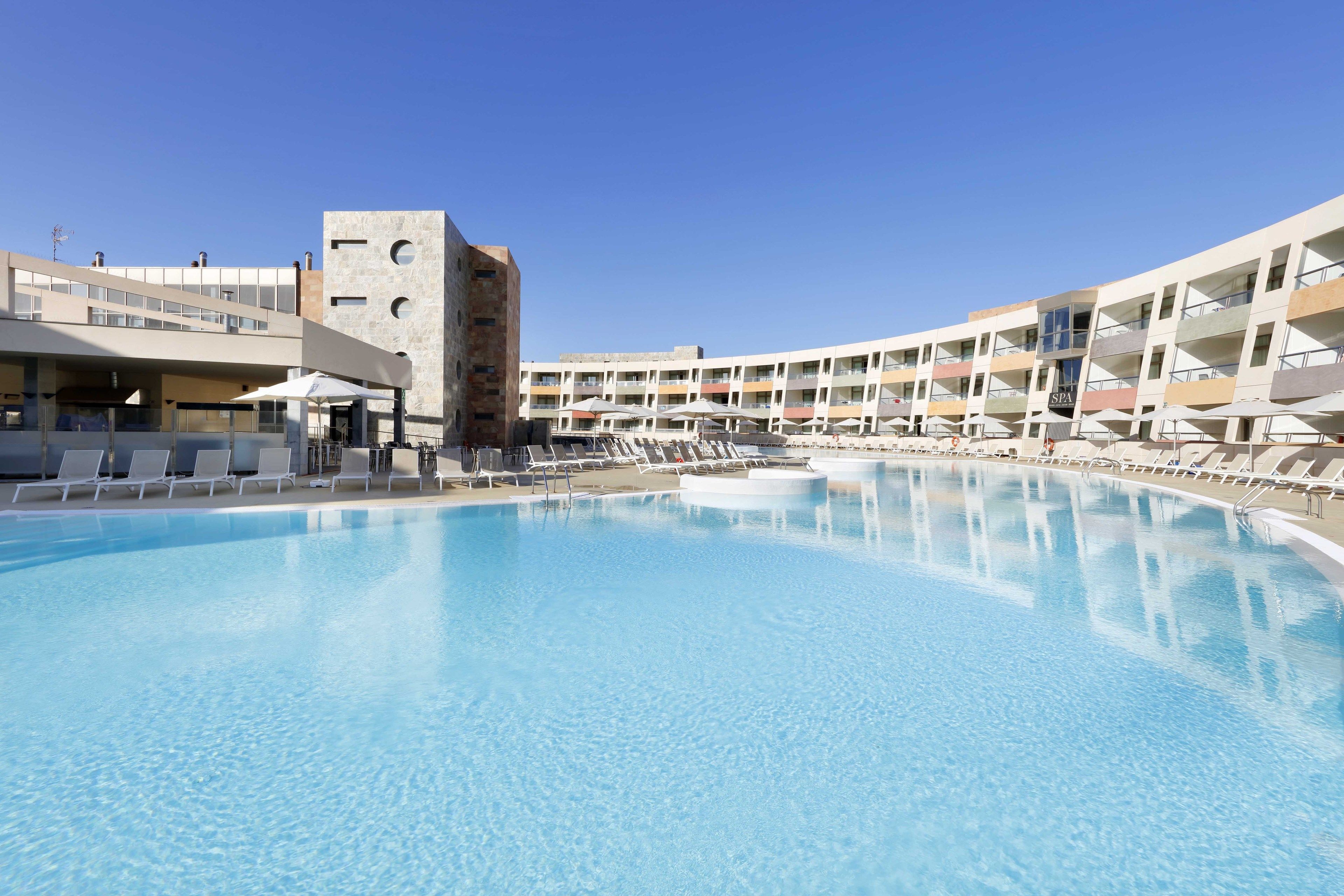 Un hotel moderno con una piscina grande, varios balcones y un área de spa.
