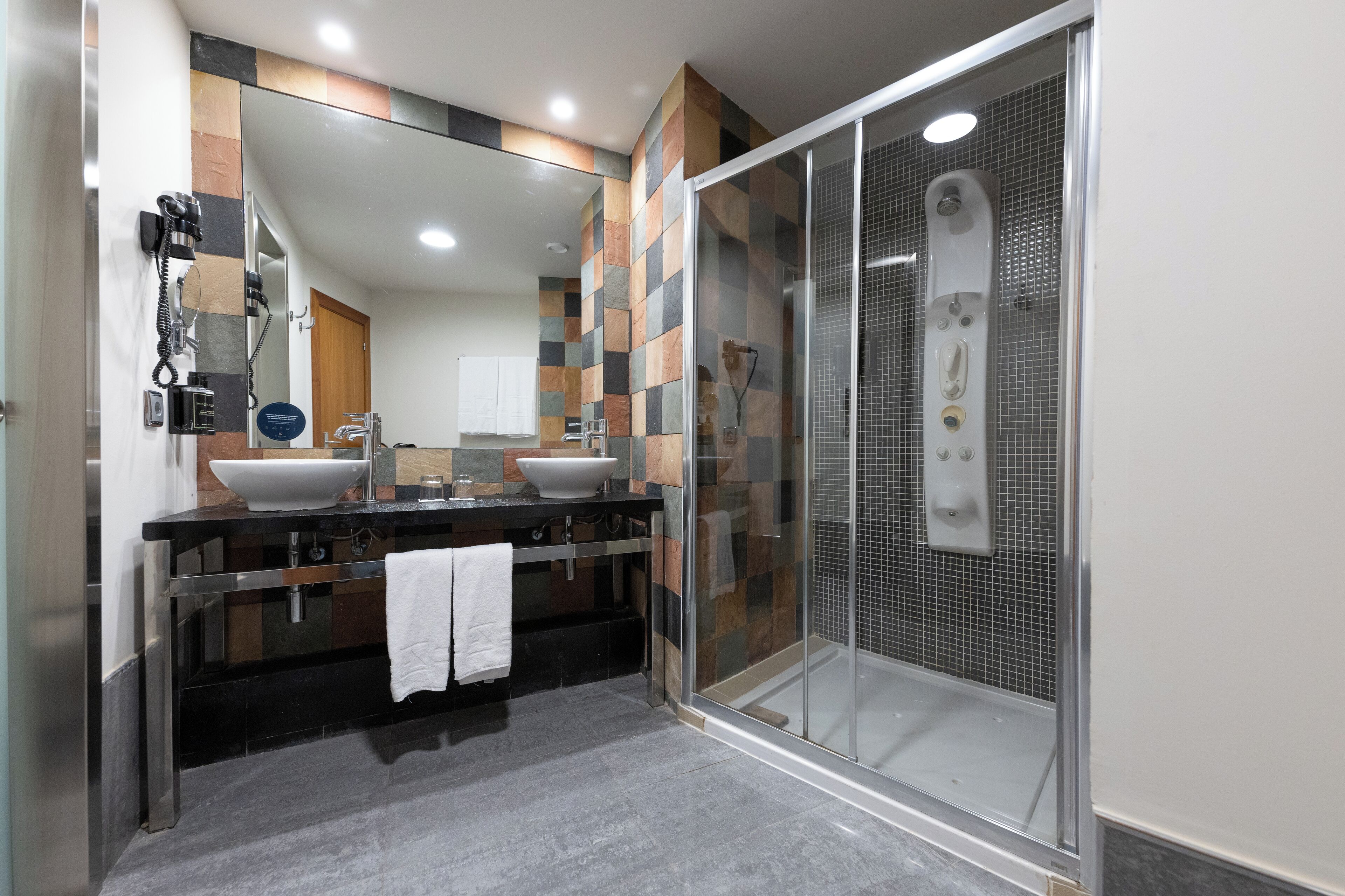 Un baño moderno con ducha acristalada, un espejo grande y un mueble de tocador doble.