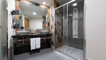 Un baño moderno con ducha acristalada, un espejo grande y un mueble de tocador doble.