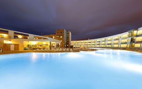 A modern hotel with a pool, lounge chairs, and a spa area.