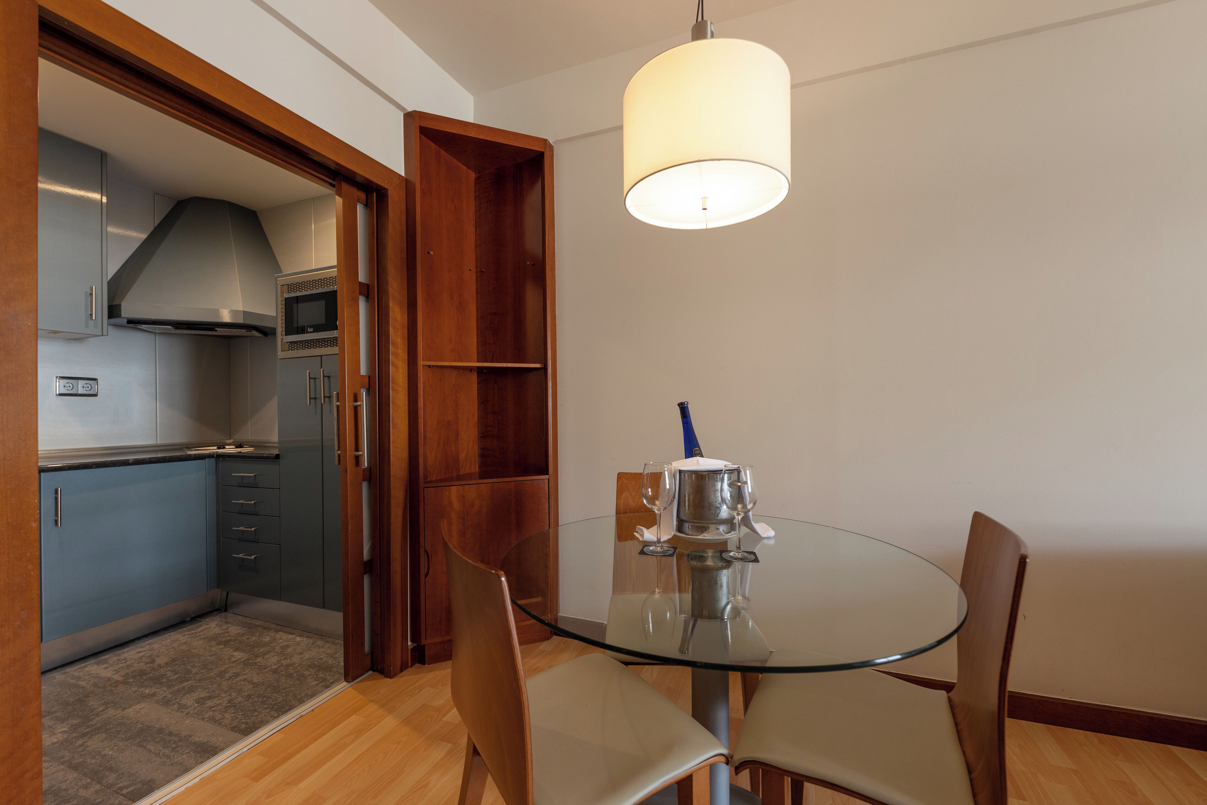 A modern kitchen with grey cabinets, a microwave, and a stainless steel range hood.