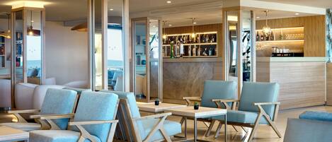 Ein moderner Lounge-Bereich mit Sitzgelegenheiten, einer Bar und Meerblick.