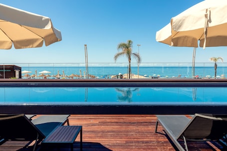 Una piscina al aire libre, sombrillas, sillones reclinables de piscina