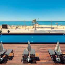 Una piscina al aire libre, sombrillas, sillones reclinables de piscina