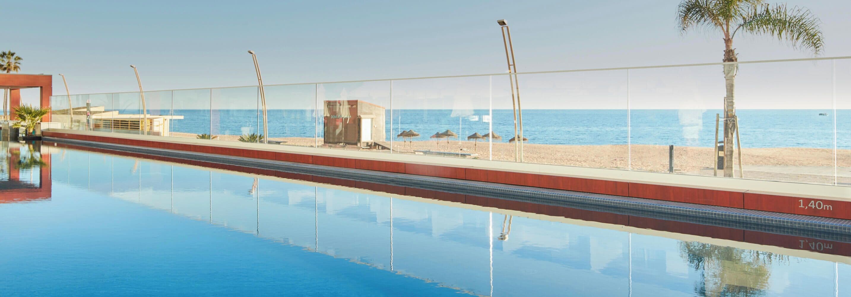 A swimming pool with a clear view of the beach and ocean.