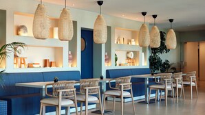A modern restaurant with blue booths, wooden chairs, and woven pendant lights. - Dom Jose Beach Hotel (Loulé)