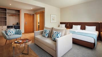 A hotel room with a sofa, a small table, a bed, and a wardrobe.