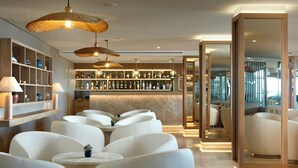 A modern bar area with white leather seating, a well-stocked liquor shelf, and ambient lighting. - Dom Jose Beach Hotel (Loulé)
