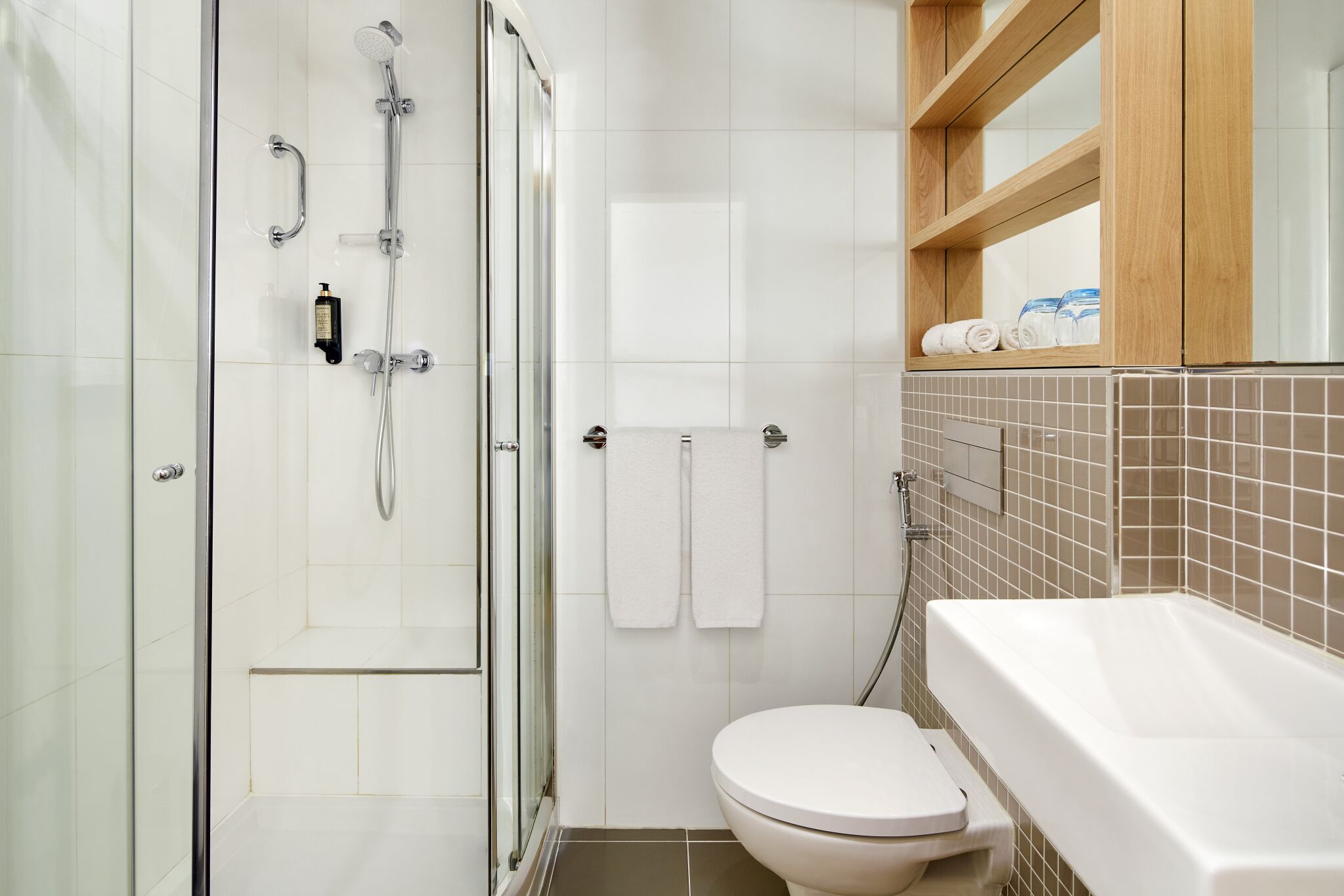 A modern bathroom with a glass shower enclosure, a white toilet, and a bathtub.