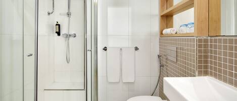 A modern bathroom with a glass shower enclosure, a white toilet, and a bathtub.