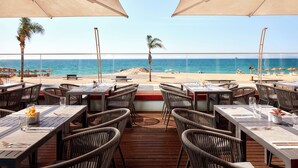 An outdoor dining area with tables and chairs, overlooking a beach and the sea. - Dom Jose Beach Hotel (Loulé)