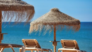 A beach with two thatched umbrellas and lounge chairs. - Dom Jose Beach Hotel (Loulé)