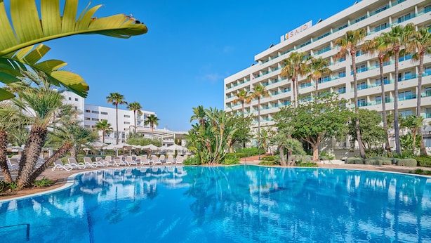 A hotel with a swimming pool, palm trees, and a clear blue sky. - Hipotels Said (Sant Llorenc des Cardassar)