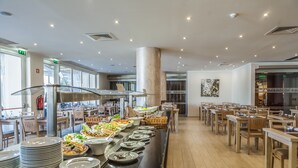 A buffet setup with multiple serving stations, a central column, and a seating area with tables and chairs. - Albufeira Sol Hotel & Spa (Albufeira)