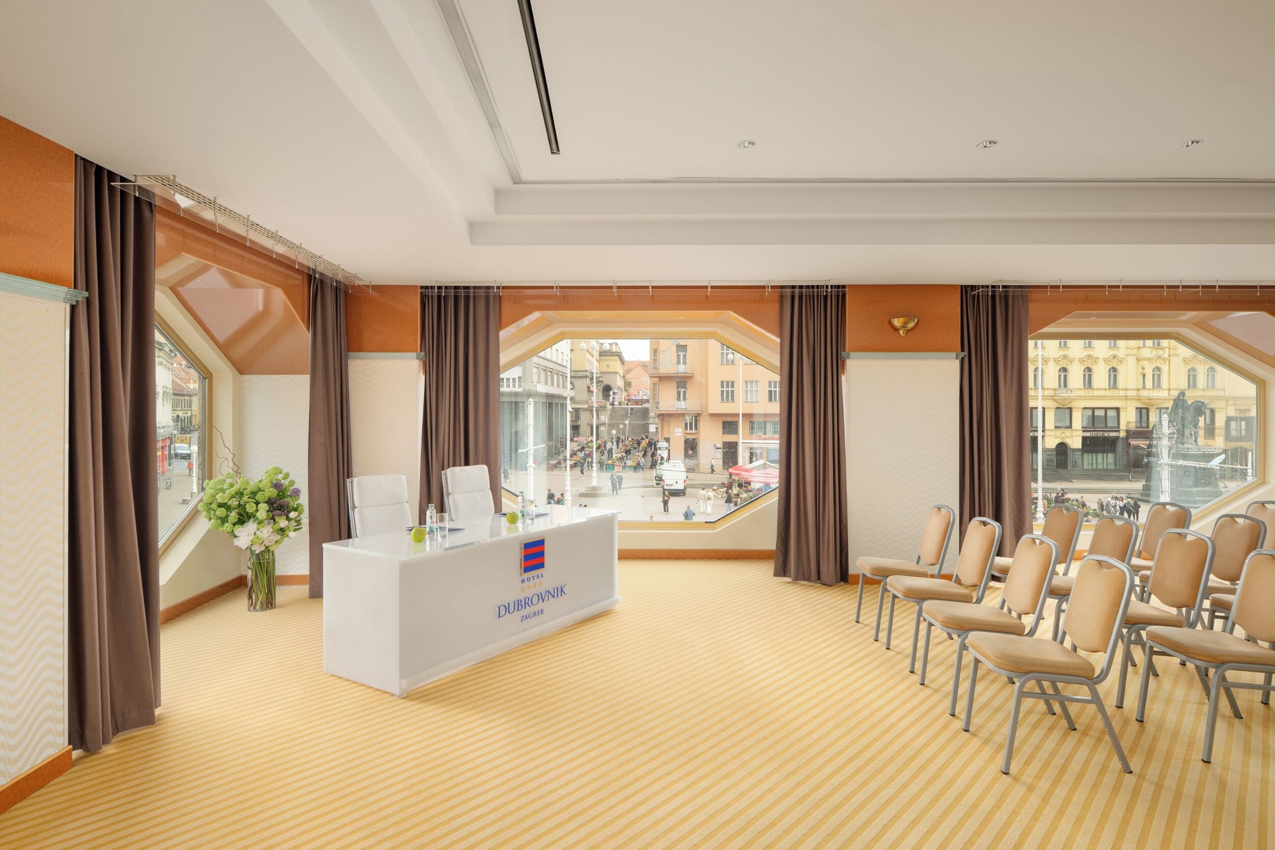 A conference room with a reception desk, chairs, and large windows offering a view of the city.