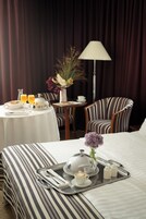 Una habitación de hotel con una cama, una bandeja con cosas para el desayuno, una lámpara y una silla.