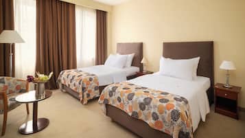 Une chambre d’hôtel avec deux lits, une petite table ronde, une chaise et une table de chevet avec une lampe.