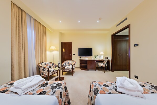 Una habitación de hotel con dos camas, un escritorio, un televisor y una silla.