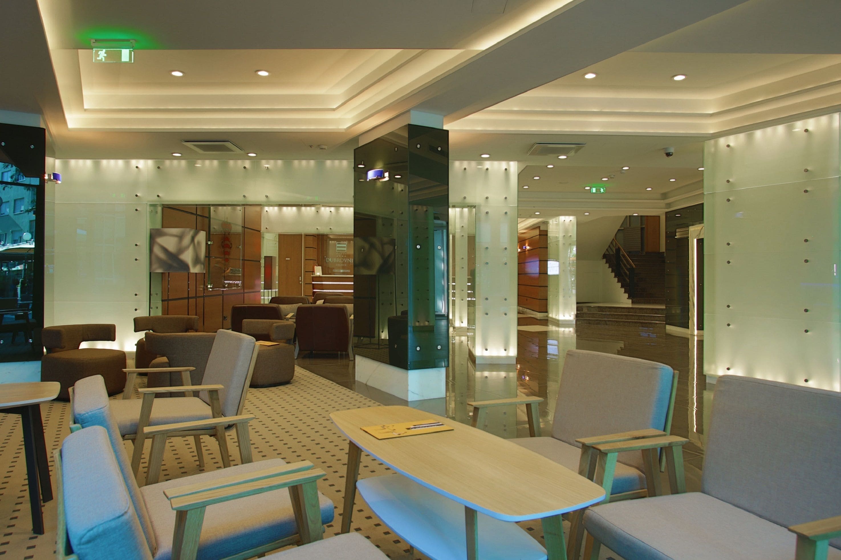 A modern lobby with seating areas, a staircase, and a reception desk.