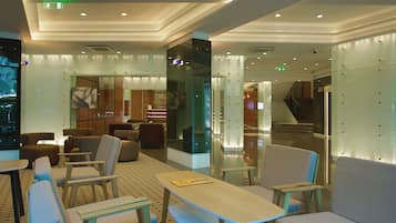 A modern lobby with seating areas, a staircase, and a reception desk.