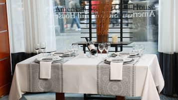 A dining table set for two with a bottle of wine, glasses, and plates.