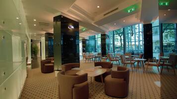 Een moderne lobby met zithoeken, grote ramen en een patroon vloer.