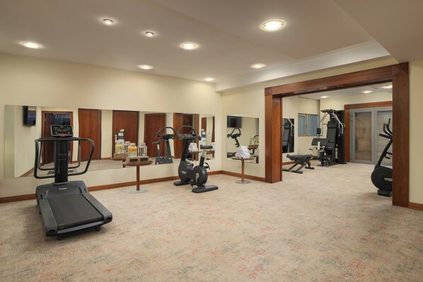Un gimnasio con cintas de correr, elípticas y equipo de pesas.
