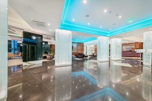 Eine moderne Hotelhalle mit poliertem Boden, Glaswänden und blauem Licht.