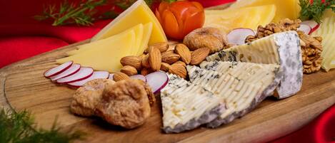Una tabla de madera con varios quesos, almendras, nueces y rábanos en rodajas.