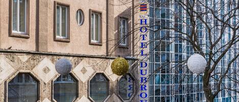 A building with a sign reading "HOTEL DUBROVNIK" and a tree with bare branches in front.