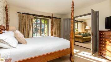 A bedroom with a four-poster bed, a wooden dresser, and a sofa in the adjacent living room.